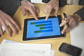Hands around digital tablet showing financial graph