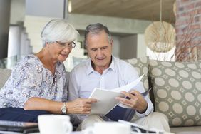 Elderly couple reviewing papers on sofa