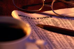 Newspaper turned to the Mutual Funds Section, with glasses, pen, and a cup of coffee