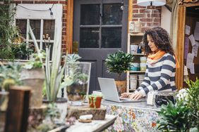 Small business owner works on laptop in an outdoor garden area