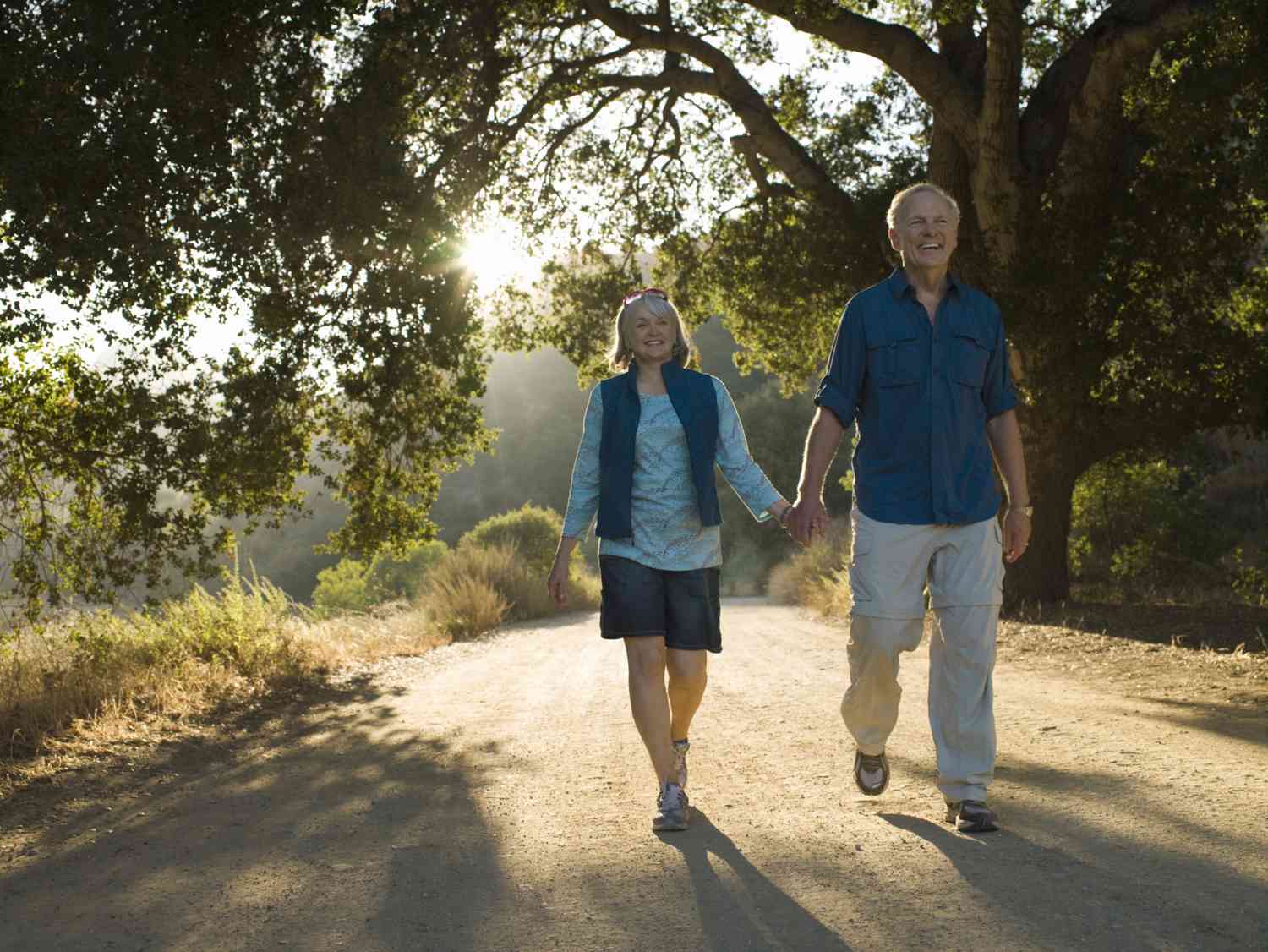 Smiling retired couple with enough savings in the bank taking a sun-filled walk in the park