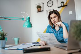 Woman with a quizzical expression examining financial documents
