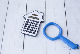 A calculator and a magnifying glass to signify figuring out a mortgage interest payment.