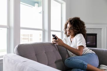 Woman sitting on couch looking at her smartphone