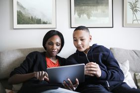 Mom and son sit on couch looking at a tablet