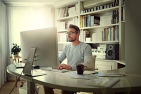  Bespectacled man working on computer form home office