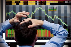 A commodities futures trader reacts to a strong downward spike and places his hands on his head.