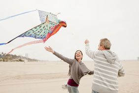 Middle agedman and woman fly a colorful kite on a beach