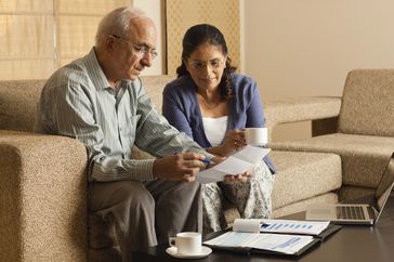 Senior couple working in living room, with laptop on coffee table