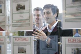 Couple looking into window with real estate listings