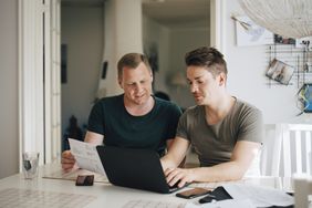 Couple looks at laptop while reviewing a paper bill