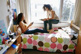 Two female college students talking and relaxing in a dorm room