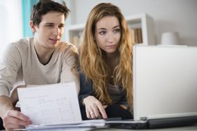 Young couple looking at a laptop and paperwork in their living room