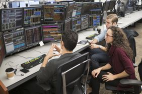 Day traders gathered around screens with charts