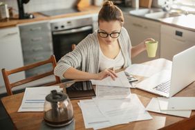 Close up of a young woman sitting in kitchen and going through her financials