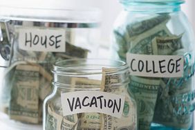 Various jars filled with money and labeled for goals of college, house, and vacation