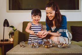 Mother and daughter putting coins in jars