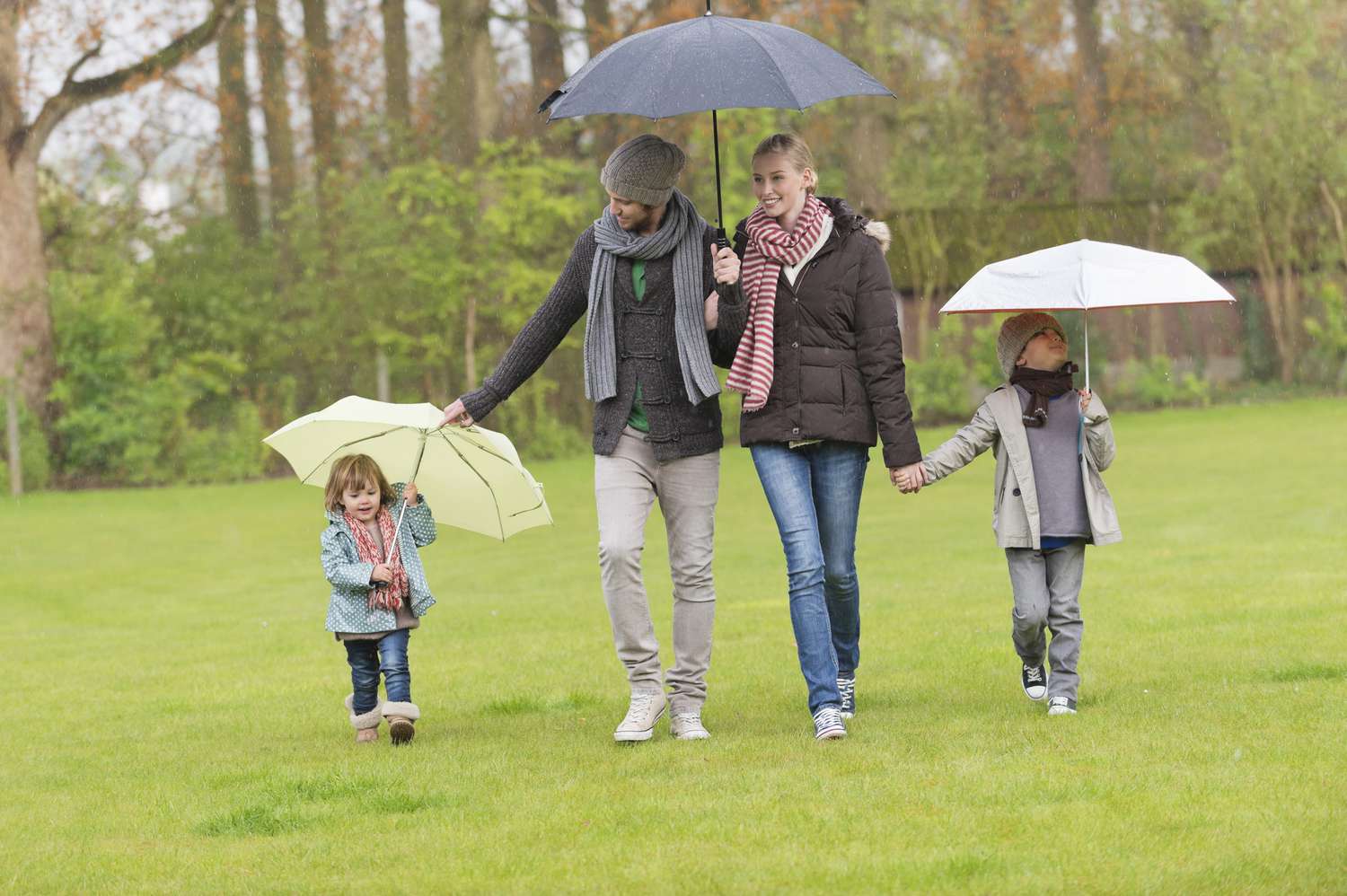 Family walking with umbrellas in a park
