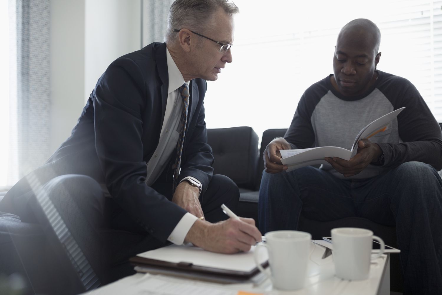 Financial advisor discussing paperwork with man in living room