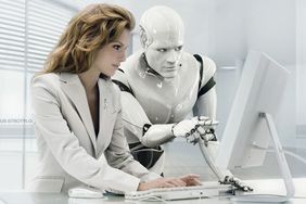 woman at computer next to a robot
