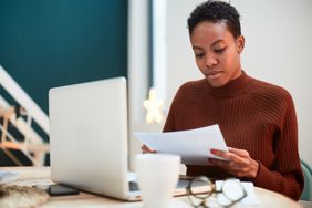 Woman working on her finances at home, filling up tax forms