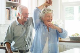 Happy senior couple dancing together at home