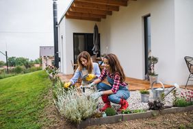 Mother and daughter gardening outside home