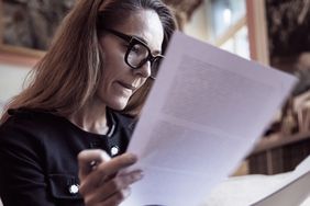 A woman wearing glasses reviews documents