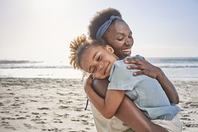 Mother hugging daughter on beach