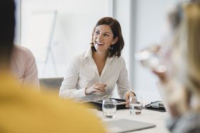 Cheerful mid adult woman smiling at business meeting