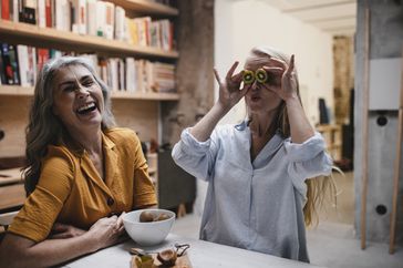 Two women playing with food and laughing