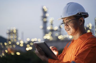 An oil worker checks production data during a shift.