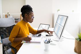Woman working on taxes at a desktop computer with an open binder