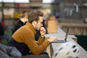 Man wearing spectacles working on a laptop