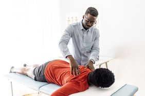 A chiropractor works on a patient who is lying on a table