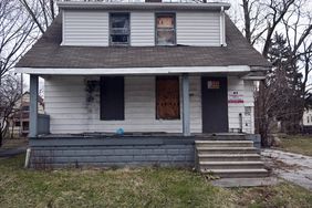 A distressed home with boarded up windows being sold as a bank owned REO property.