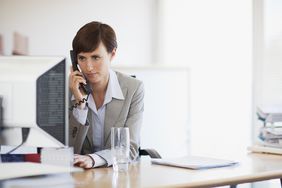 Businesswoman working at computer and talking on phone