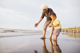 A grandparent and grandchild play on the beach.