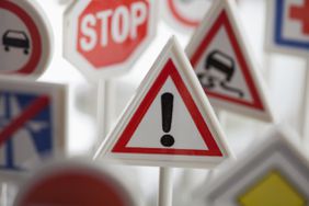 A toy hazard sign surrounded by other various road warning signs