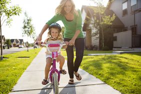 Mom helping daughter ride a bike