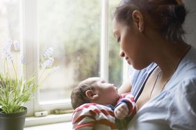 Mother holding a newborn baby beside a window