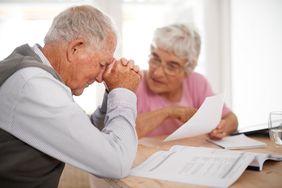 Distressed retired couple looking at paperwork and frowning