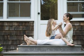 A parent and child hold hands on a front porch.