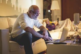 Older man in white shirt using a laptop