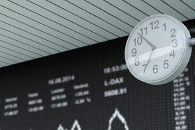 A clock in front of a stock ticker