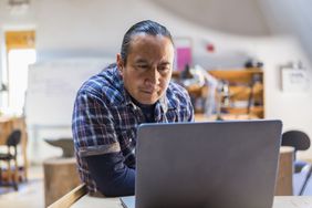 Native American man using a laptop in art studio