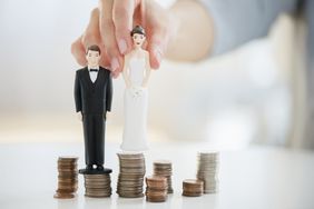 Bride and groom as game pieces standing on top of coin stacks
