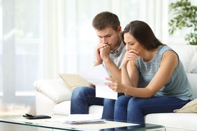 Concerned couple on a sofa, looking at paperwork