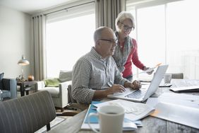 An older couple working together on a laptop.