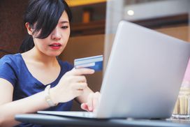 Young Japanese woman using her credit card to do online shopping